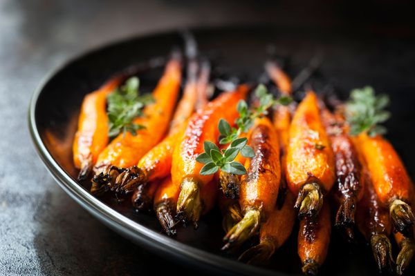 A close-up of roasted carrots with sprigs of thyme